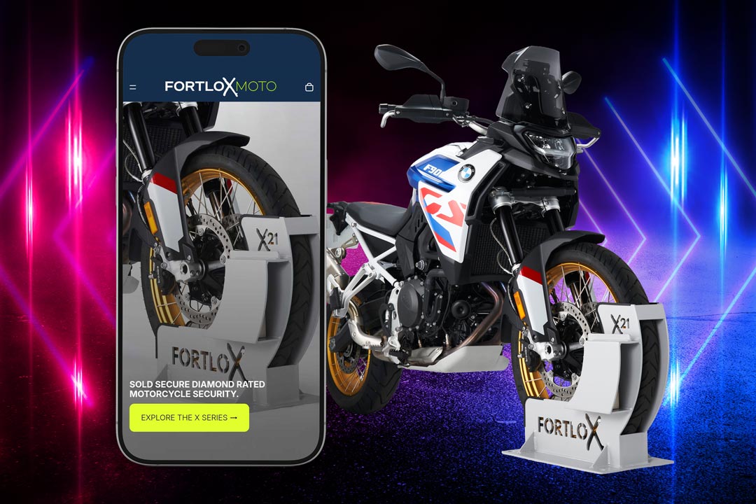 The Fortlox Moto website made by G&V Bristol displayed on a mobile phone next to a BMW motorcycle.
