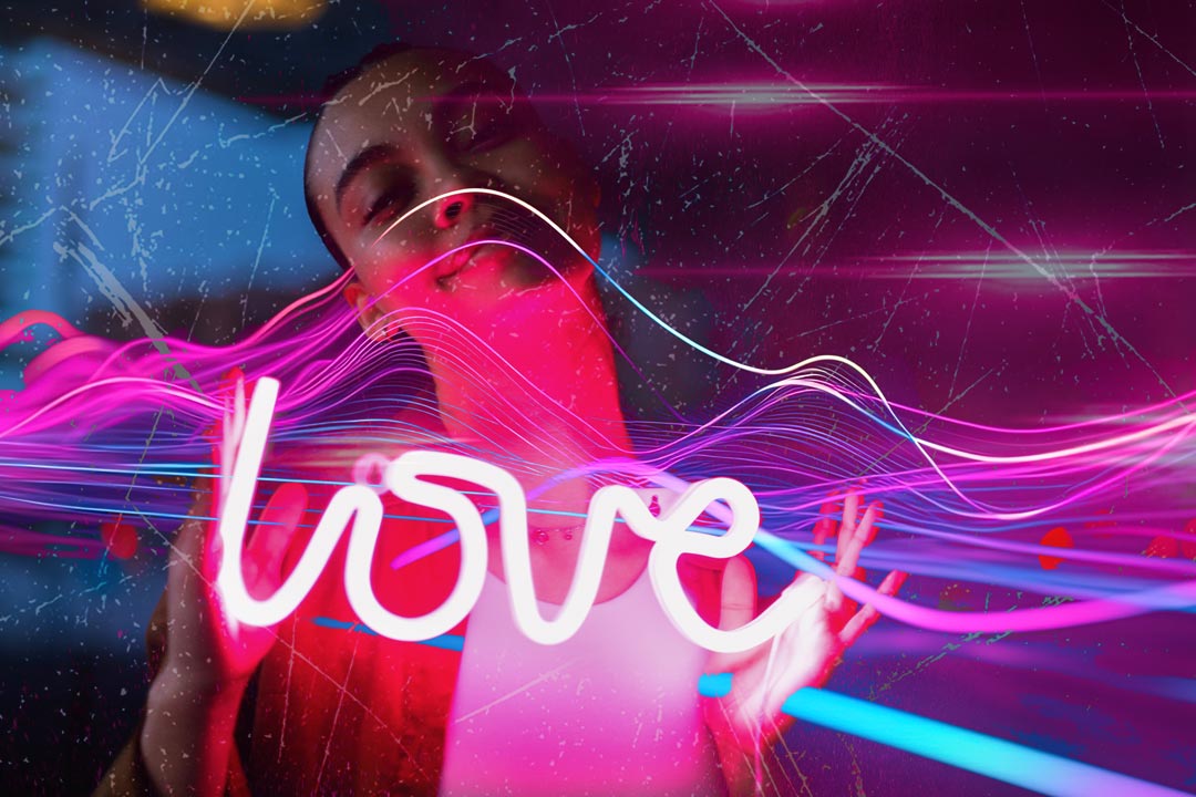Person with 'love' neon sign surrounded by colorful light effects